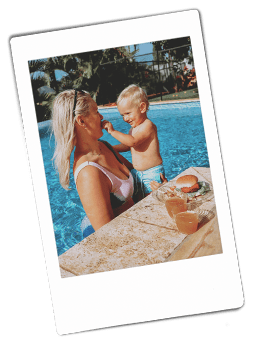 Instax picture of a mother and son standing in a pool with a burger plated on a Chinet Crystal plate next to them on the side of the pool