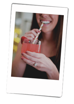 A woman drinking a drink out of Chinet Crystal cup with a straw