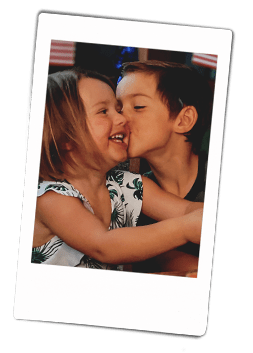 Instax picture of a young brother giving his sister a kiss on her cheek