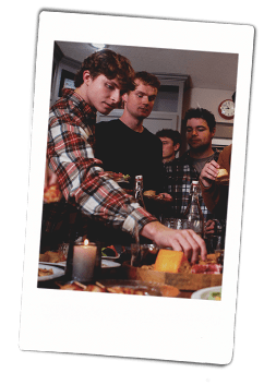 Instax picutre of a group of friends eating around a kitchen island filled with appetizers