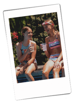 Instax picture of girls sitting on the side of a pool drinking from Chinet Crystal cups