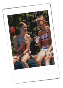 Instax picture of girls sitting on the side of a pool drinking from Chinet Crystal cups