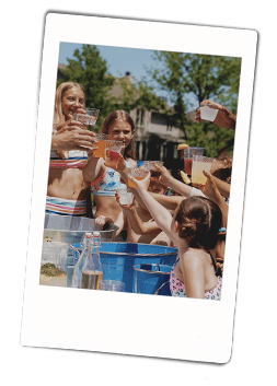 Kids at a pool party holding up Chinet Crystal cups to cheers