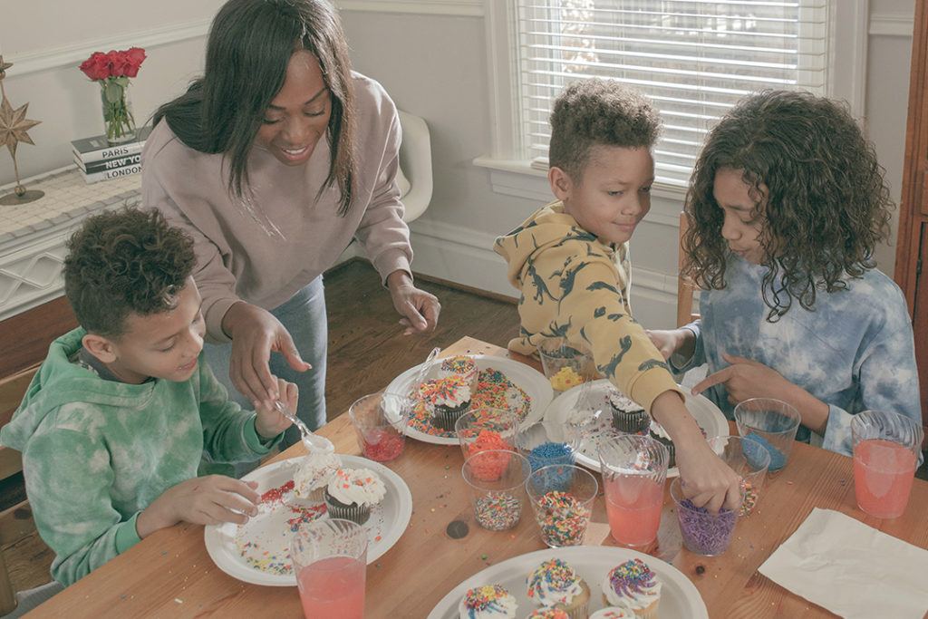 Mom and three children decorating cupcakes