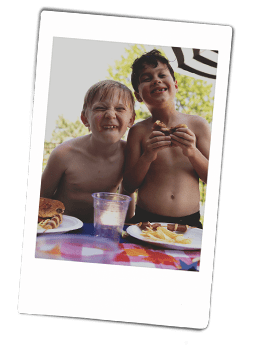 Instax picture of two boys smiling and eating hamburgers