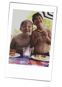 Instax picture of two boys smiling and eating hamburgers