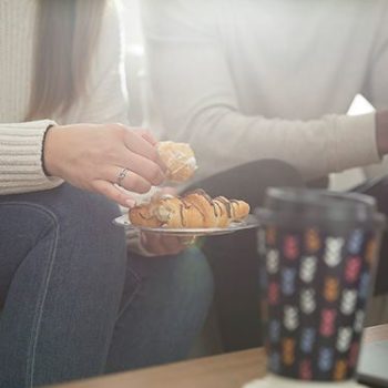 Two people eating pastries and drinking from Chinet Comfort cups