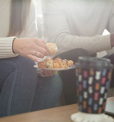 Two people eating pastries and drinking from Chinet Comfort cups