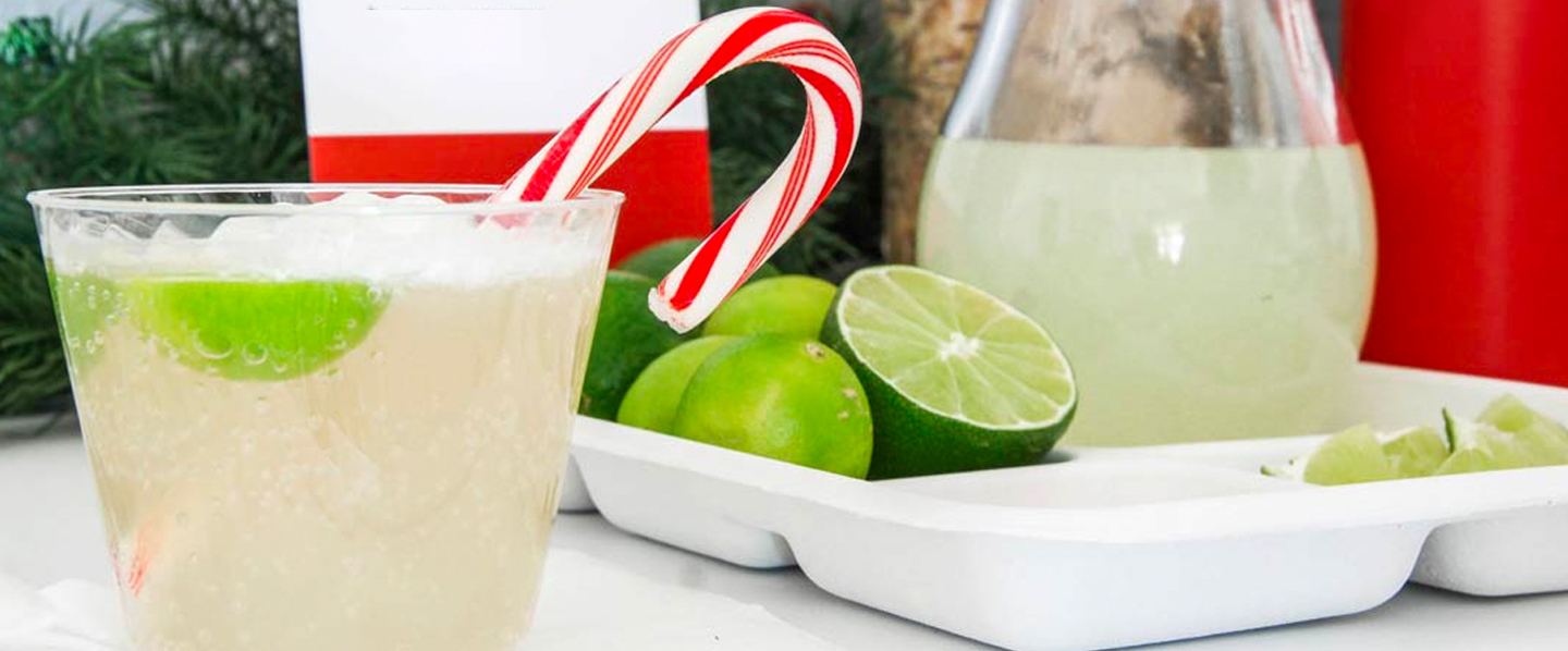 Holiday drink in Chinet Crstyal cup with candy cane stirrer and limes in background