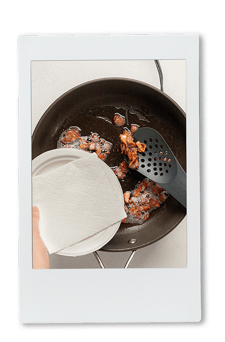 Instax of scooping bacon out of a cast iron pan on a Chinet Classic lunch plate