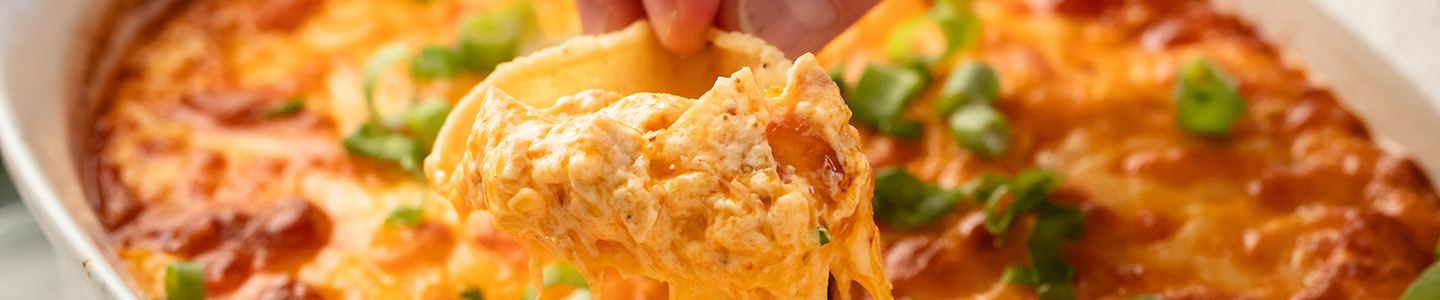 Tortilla chipped dipping into cheesy buffalo chicken dip