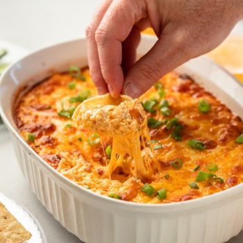 Tortilla chipped dipping into cheesy buffalo chicken dip