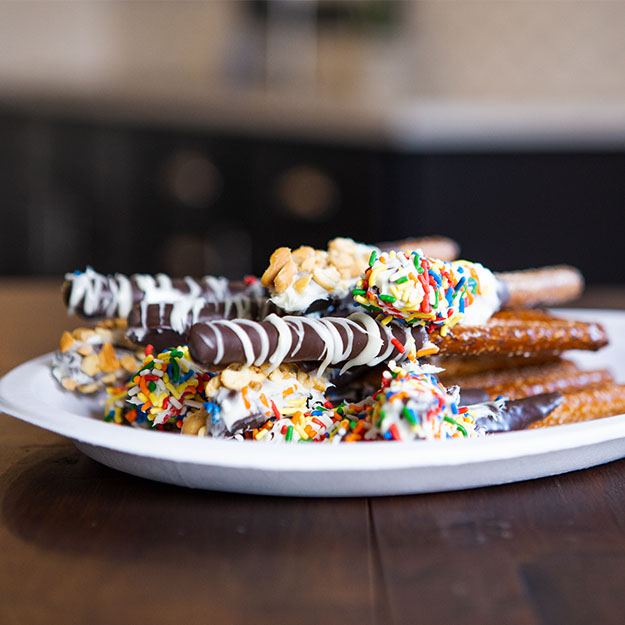 Frosting-dipped pretzel rods served on a Chinet Classic plate