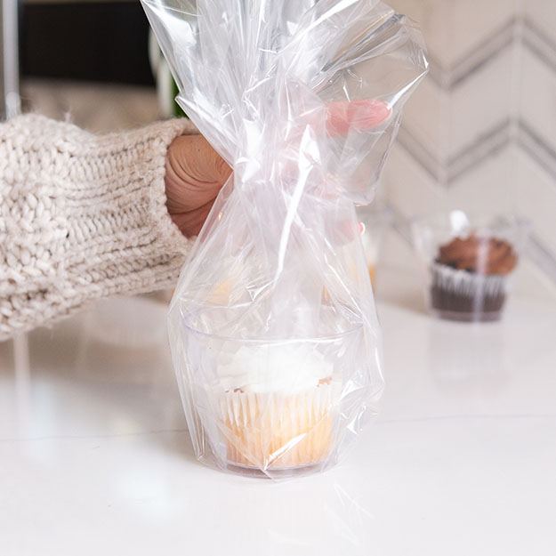 Woman wrapping a Chinet Crystal 9oz cup with clear wrap