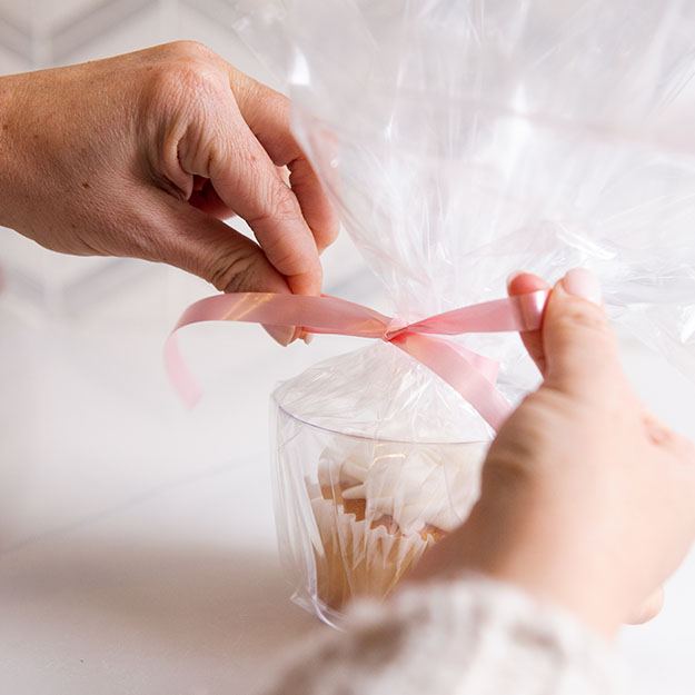 Woman wrapping a Chinet Crystal 9oz cup with clear wrap