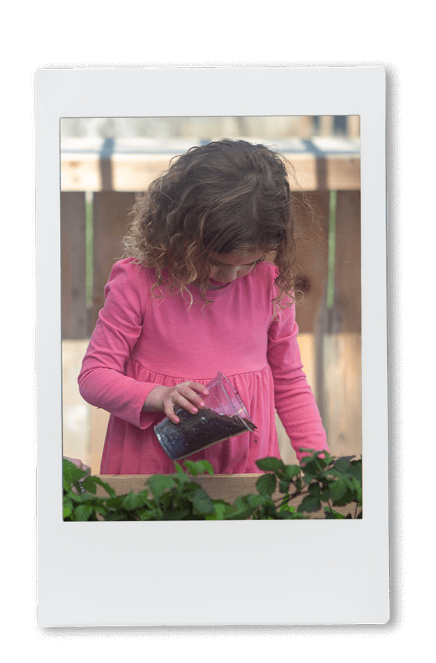 Instax picture of a girl pouring dirt into an herb garden