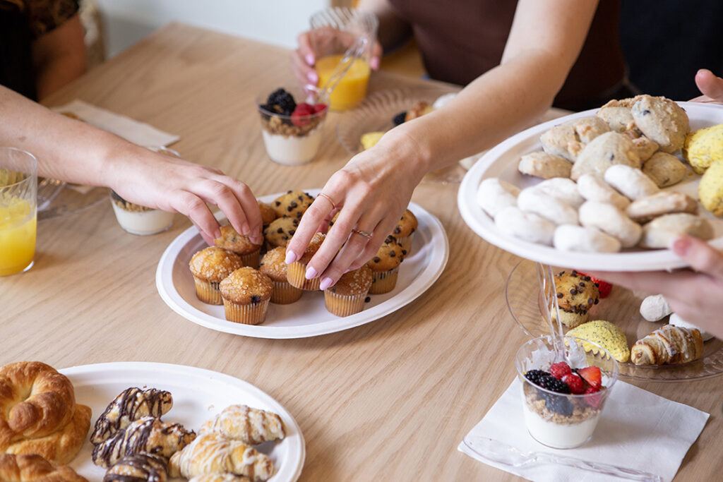 Women grabbing muffins off of a Chinet Classic plate