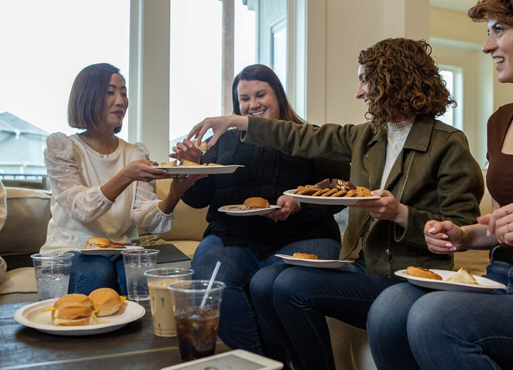 Women sitting on a couch eating appetizers