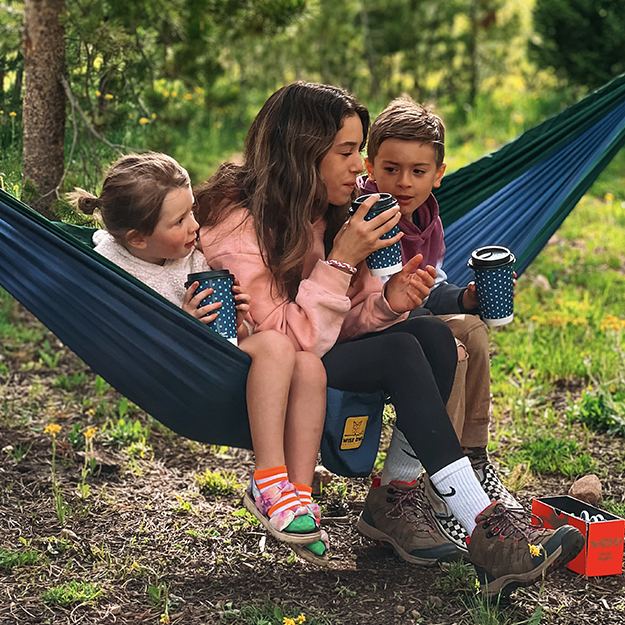 Siblings sitting in a hammock holding Chinet Comfort cups