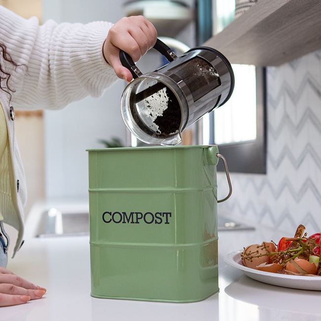 Woman pouring coffee grounds in a compost pin