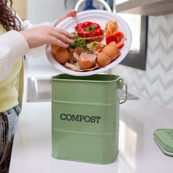 Woman pouring a plate full of leftover food in a compost bin