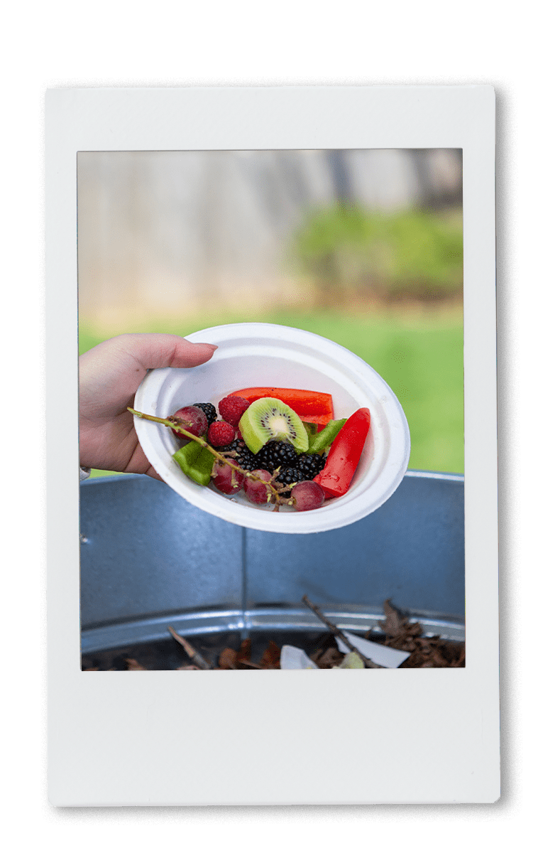 Woman pouring a plate full of leftover food in a compost bin