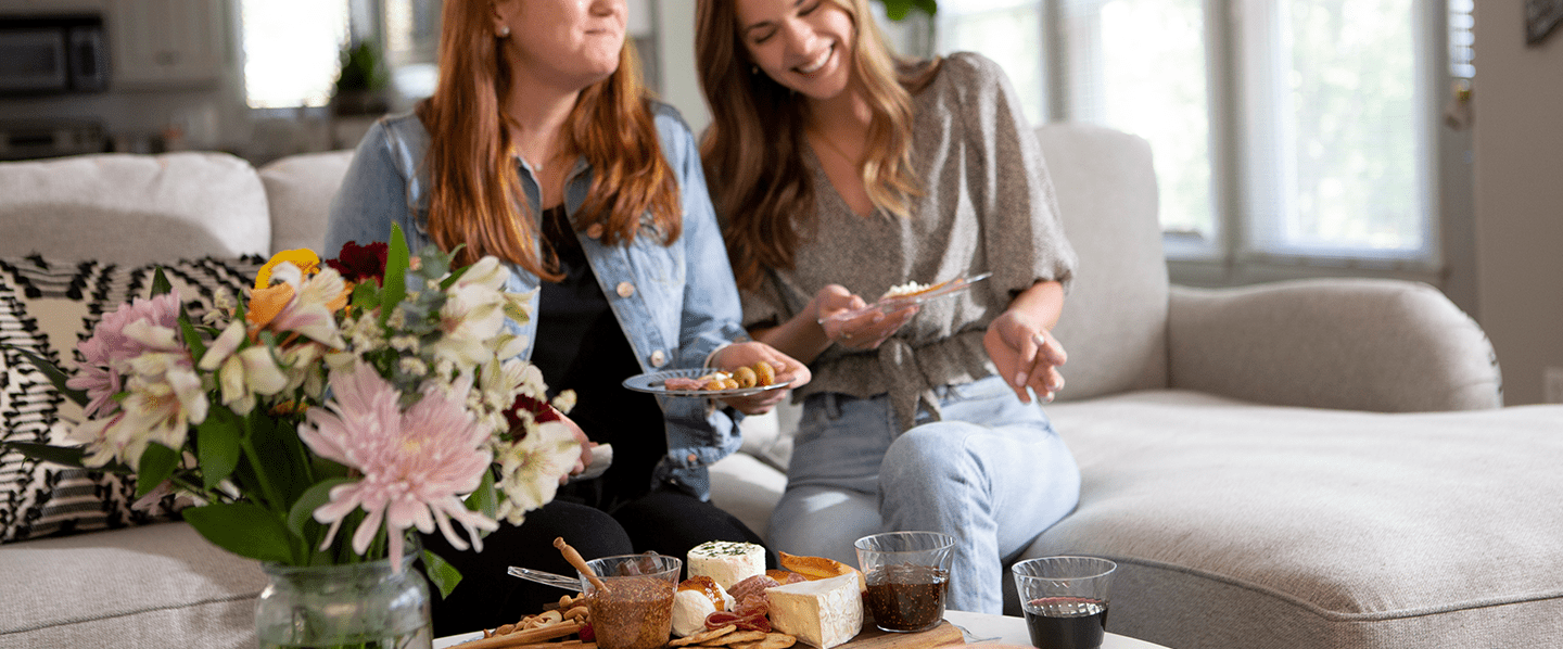 Women laughing on a couch eating brunch