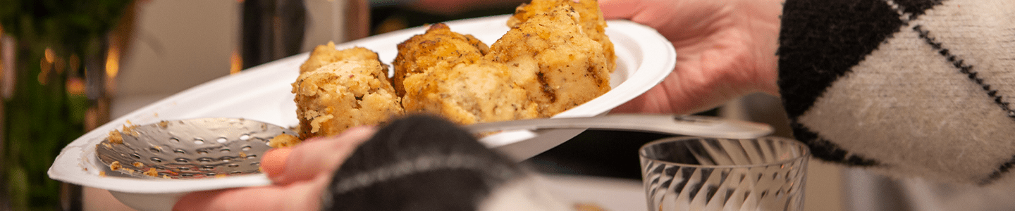 Woman passing a breaded chicken slices on a Chinet Classic plate