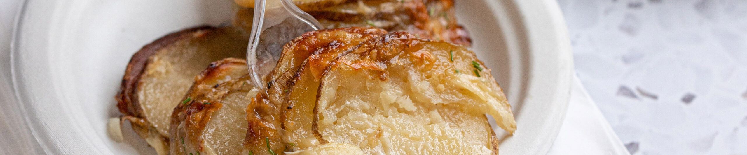 Cheesy Hassleback potatoes served on a Chinet Classic plate