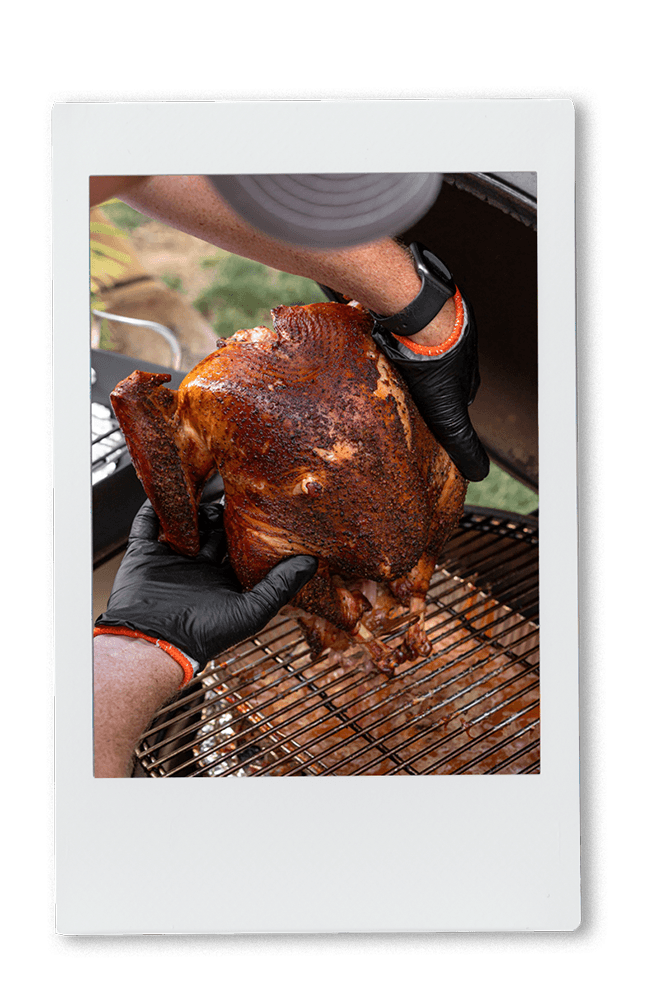 Instax picture of man picking up a smoked turkey from a smoker BBQ