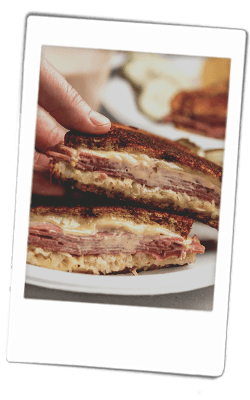 Instax picture of a Reuben grilled cheese sandwich served on Chinet Classic plates