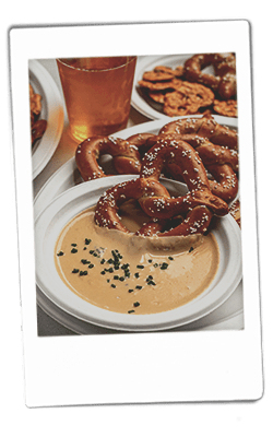 Instax picture of a pretzel be dipping into a bowl of beer cheese dip