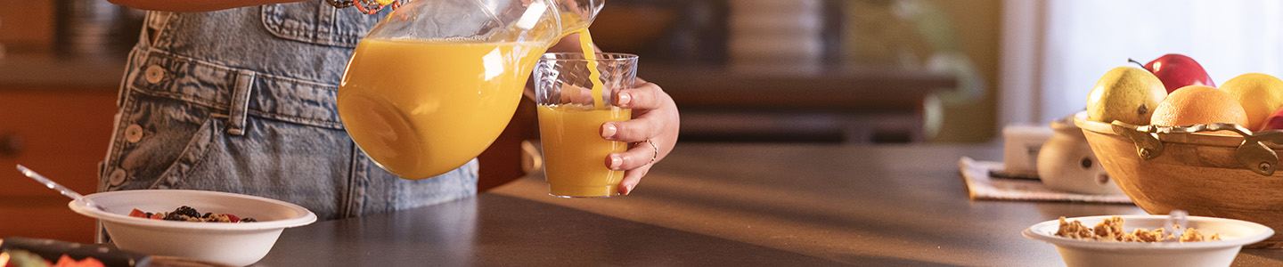 Orange juice poured from a pitcher to a Chinet Crystal cup