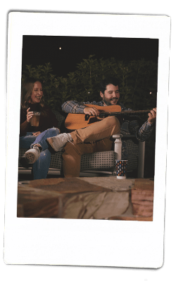 Instax of a man playing guitar by a bonfire with chinet products