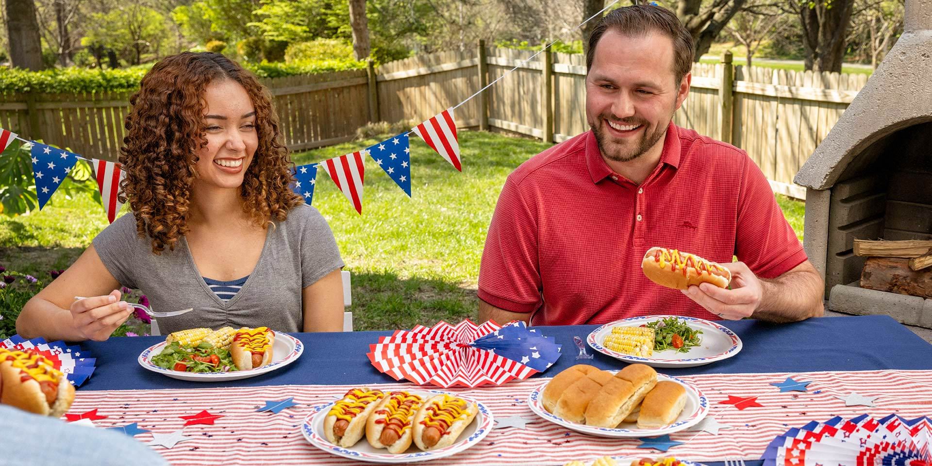 People enjoying hot dogs on Chinet Classic Dinner America’s Plates at an outdoor cookout