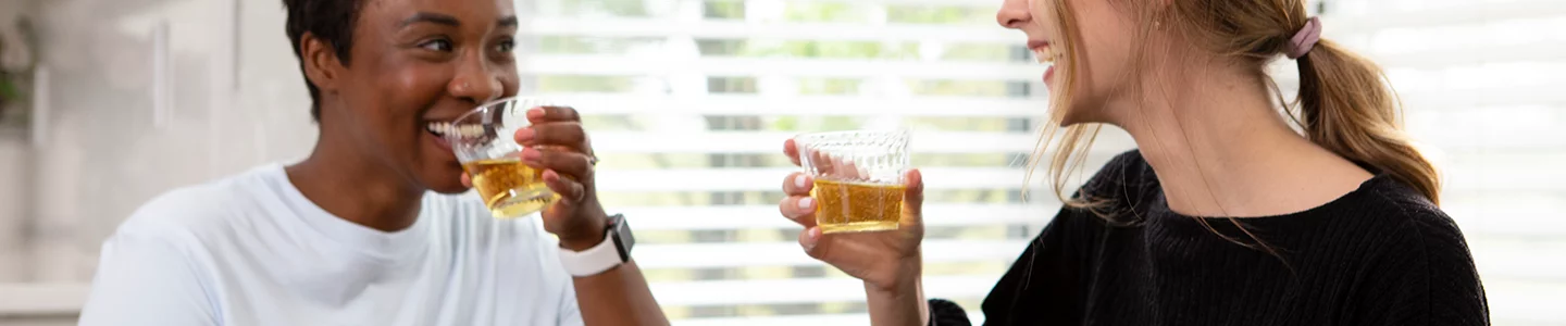 Two women talking to each other and drinking wine from a Chinet Crystal cup