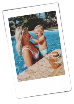Instax picture of a mother and son standing in a pool with a burger plated on a Chinet Crystal plate next to them on the side of the pool