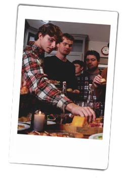 Instax picutre of a group of friends eating around a kitchen island filled with appetizers