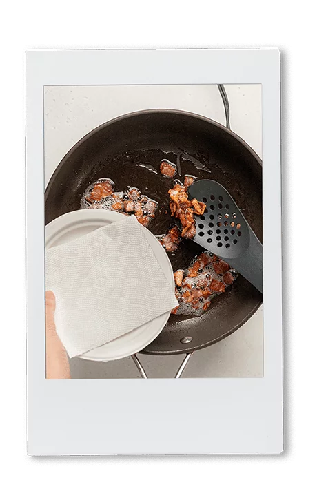Instax of scooping bacon out of a cast iron pan on a Chinet Classic lunch plate