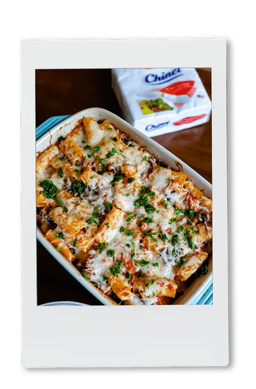 Instax of a cheesy pasta bake in a baking dish next to Chinet Classic napkins