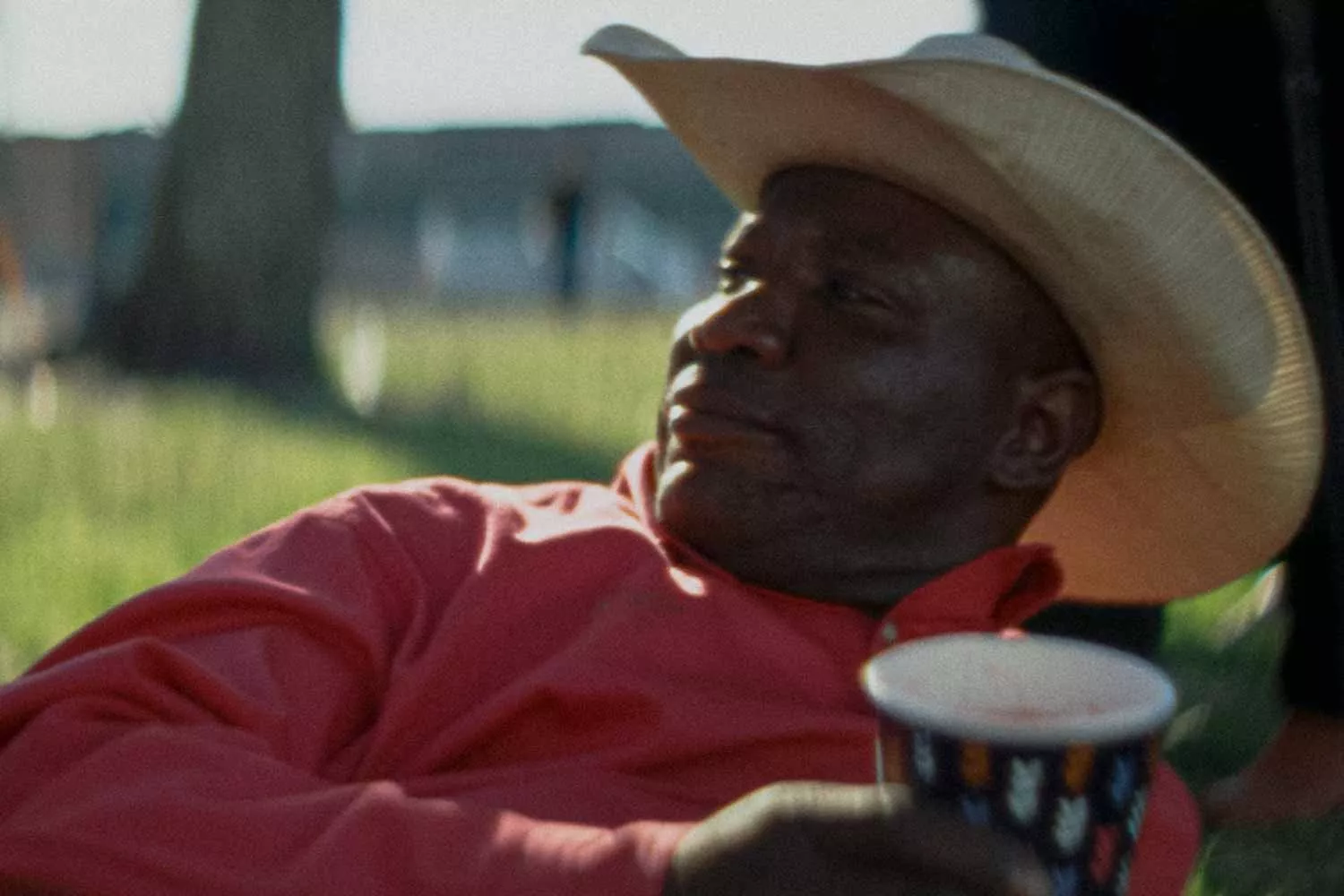 A man lounging in a cowboy hat with a Chinet Comfort® cup in his hand