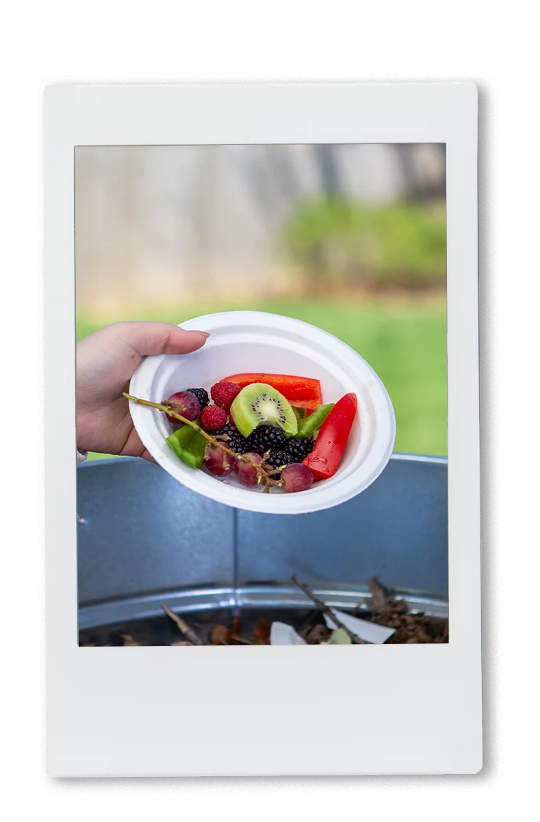 Woman pouring a plate full of leftover food in a compost bin