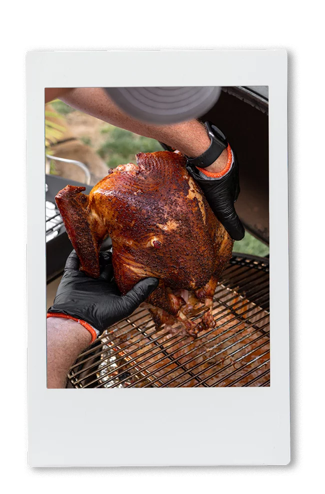 Instax picture of man picking up a smoked turkey from a smoker BBQ