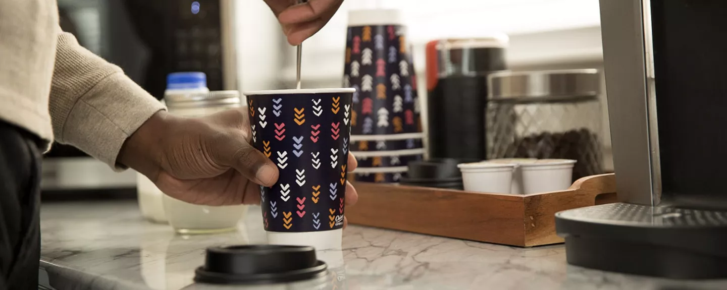 Man's hand stirring a spoon in a Chinet Comfort cup