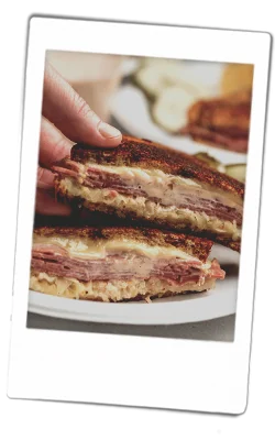 Instax picture of a Reuben grilled cheese sandwich served on Chinet Classic plates